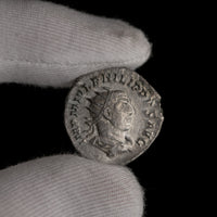 Roman silver antoninianus of Philip I shown in hand for context.
