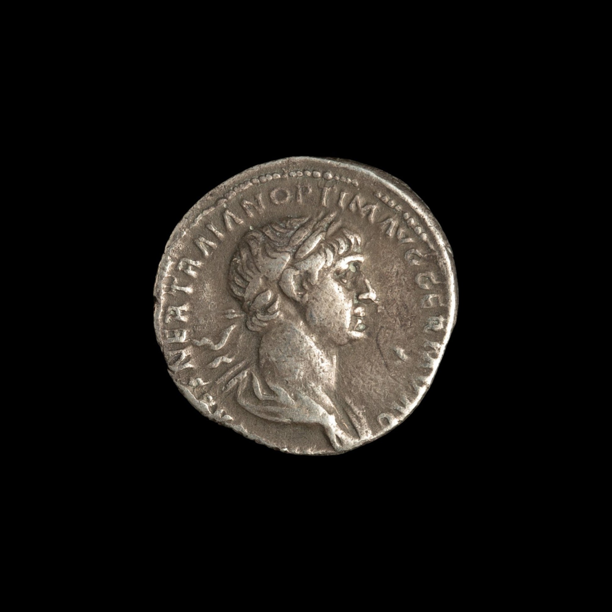 Obverse of Roman silver denarius of Trajan, legend IMP CAES NER TRAIAN OPTIM AVG GERM DAC, radiate or laureate bust right.