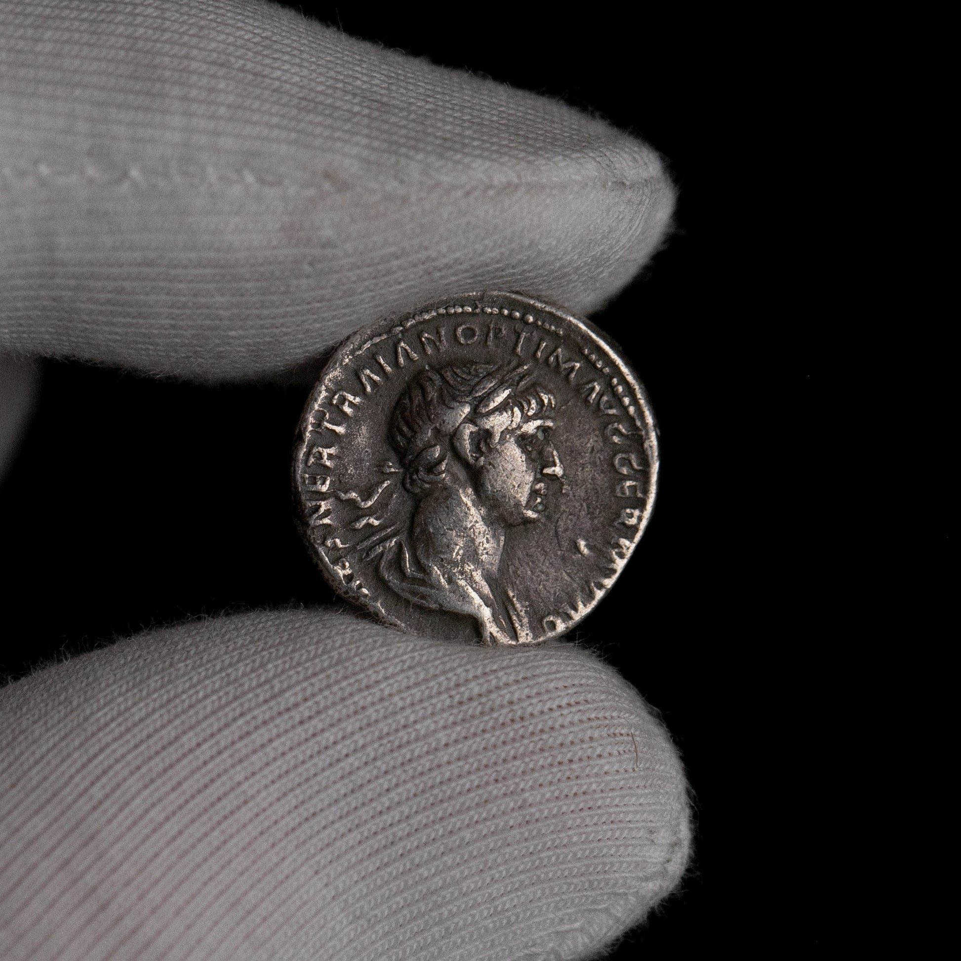 Roman silver denarius of Trajan held for size reference.