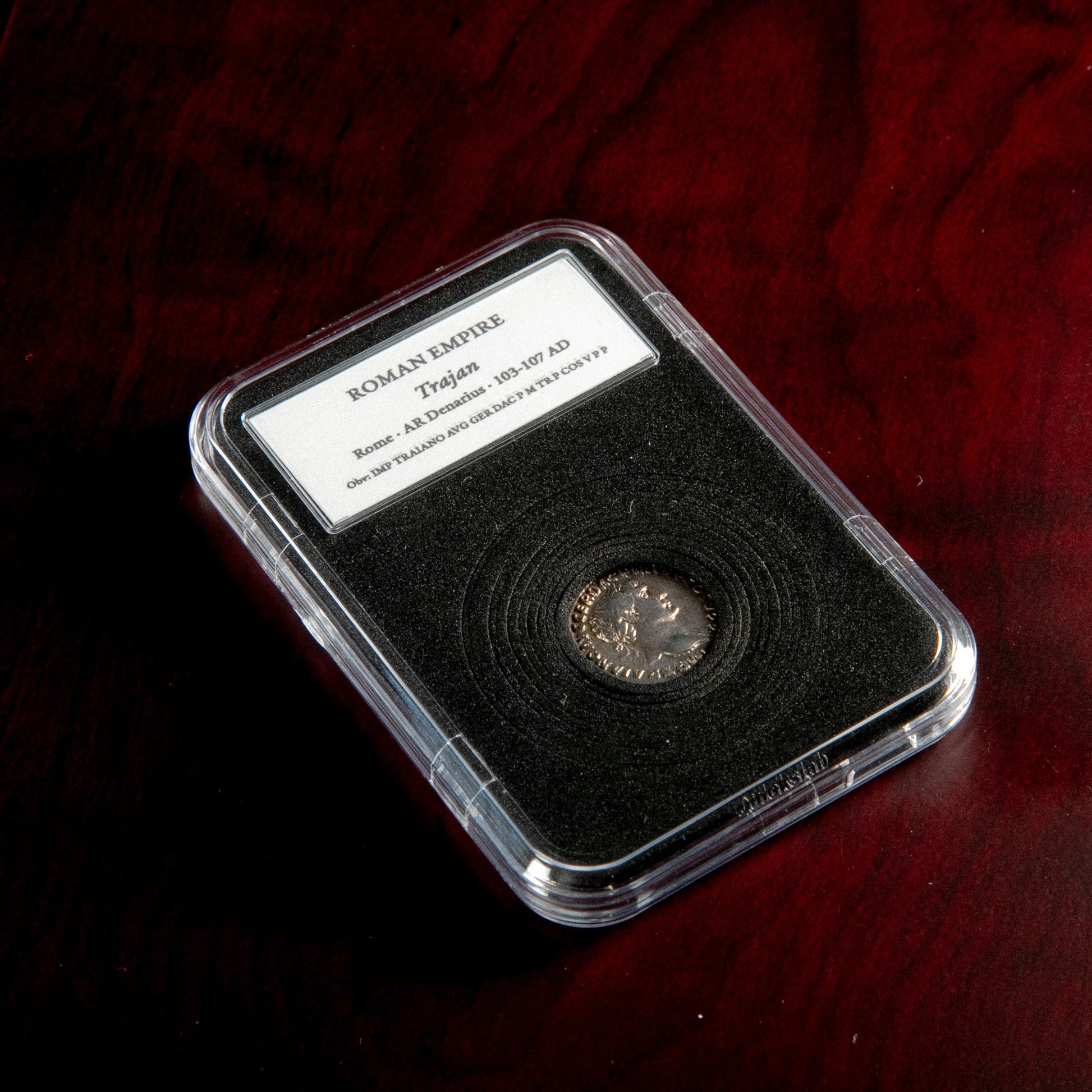 Roman silver denarius of Trajan in protective slab with catalog label.