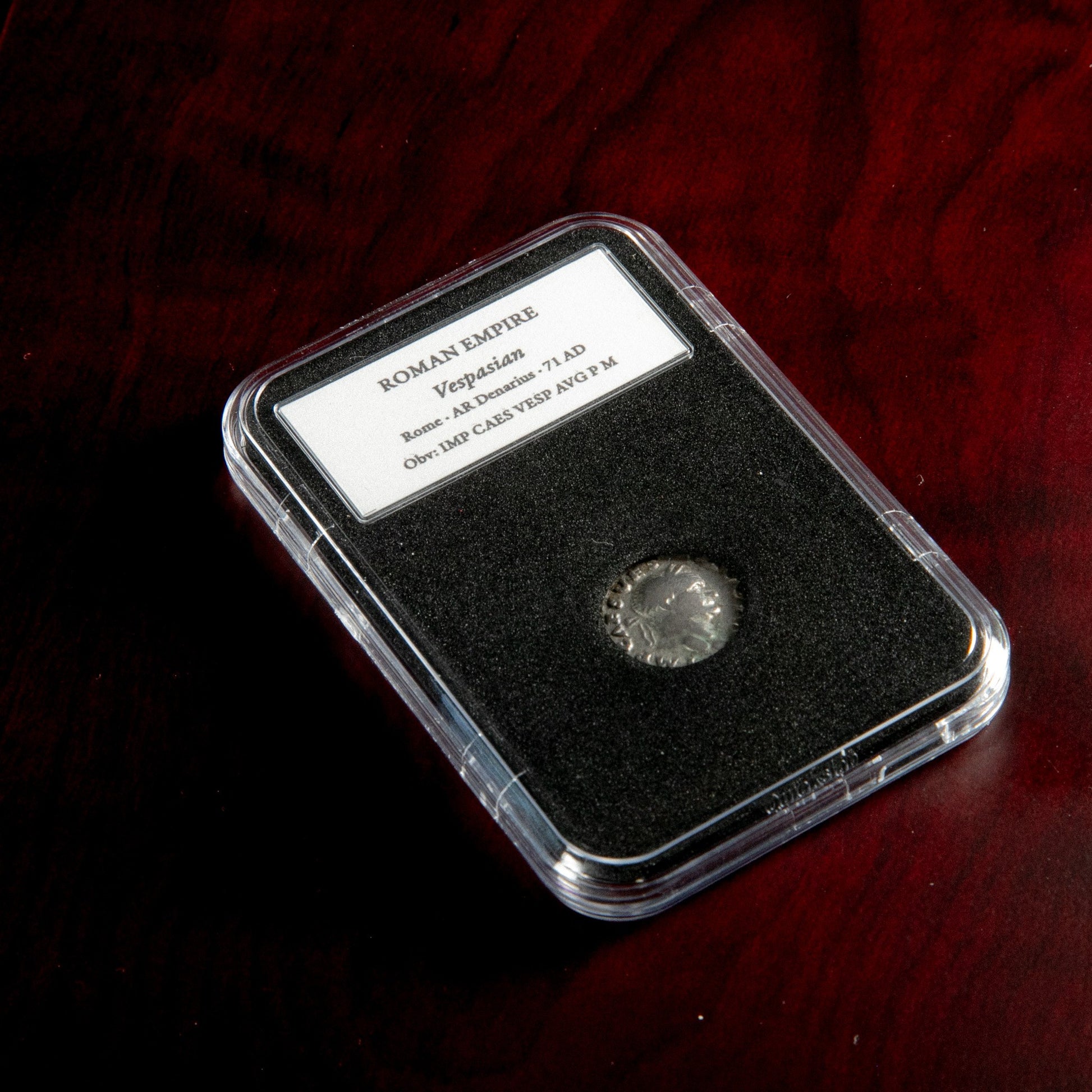 Roman silver denarius of Vespasian in protective slab with catalog label.