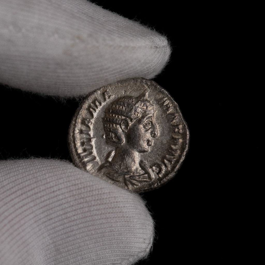 Roman silver denarius of Julia Mamaea held for size reference.