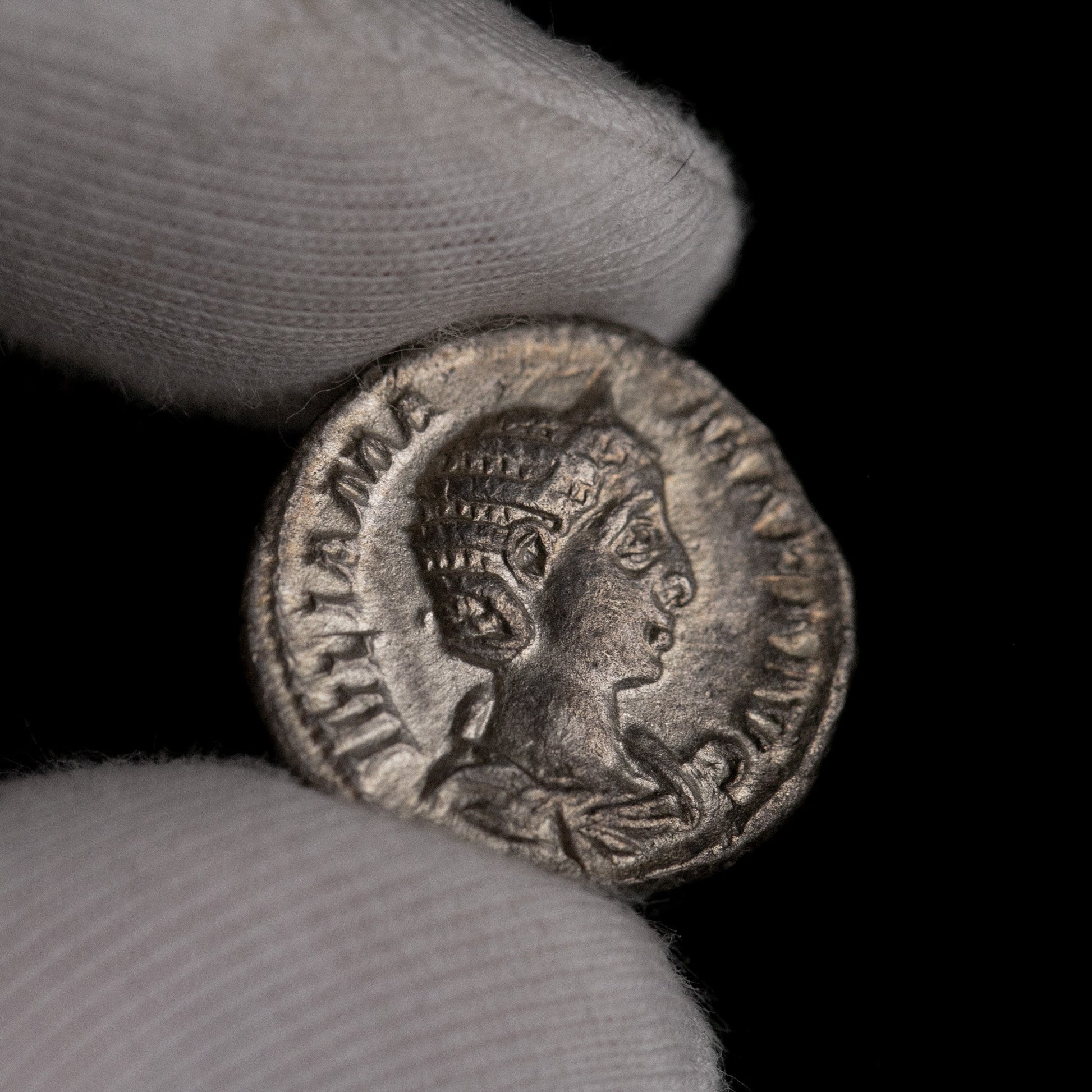 Roman silver denarius of Julia Mamaea held for size reference.