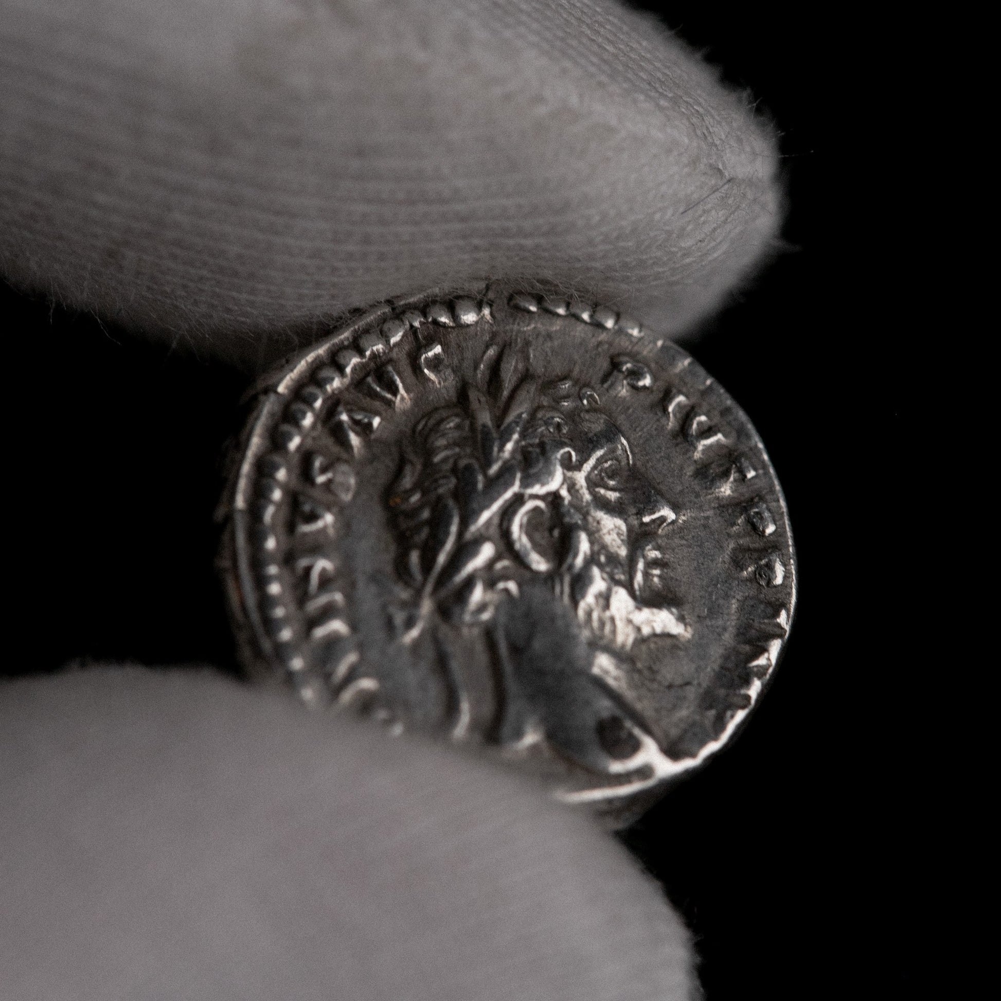 Macro detail of Roman silver denarius of Antoninus Pius, portrait close-up.