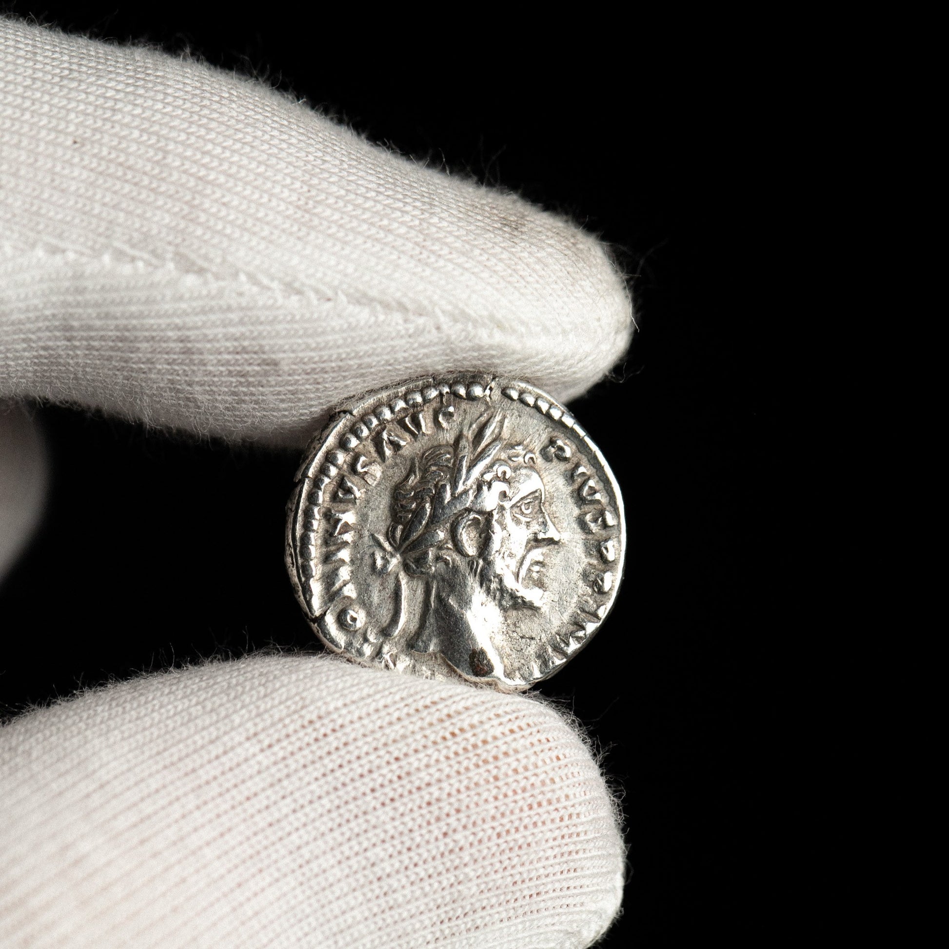 Roman silver denarius of Antoninus Pius shown in hand for context.