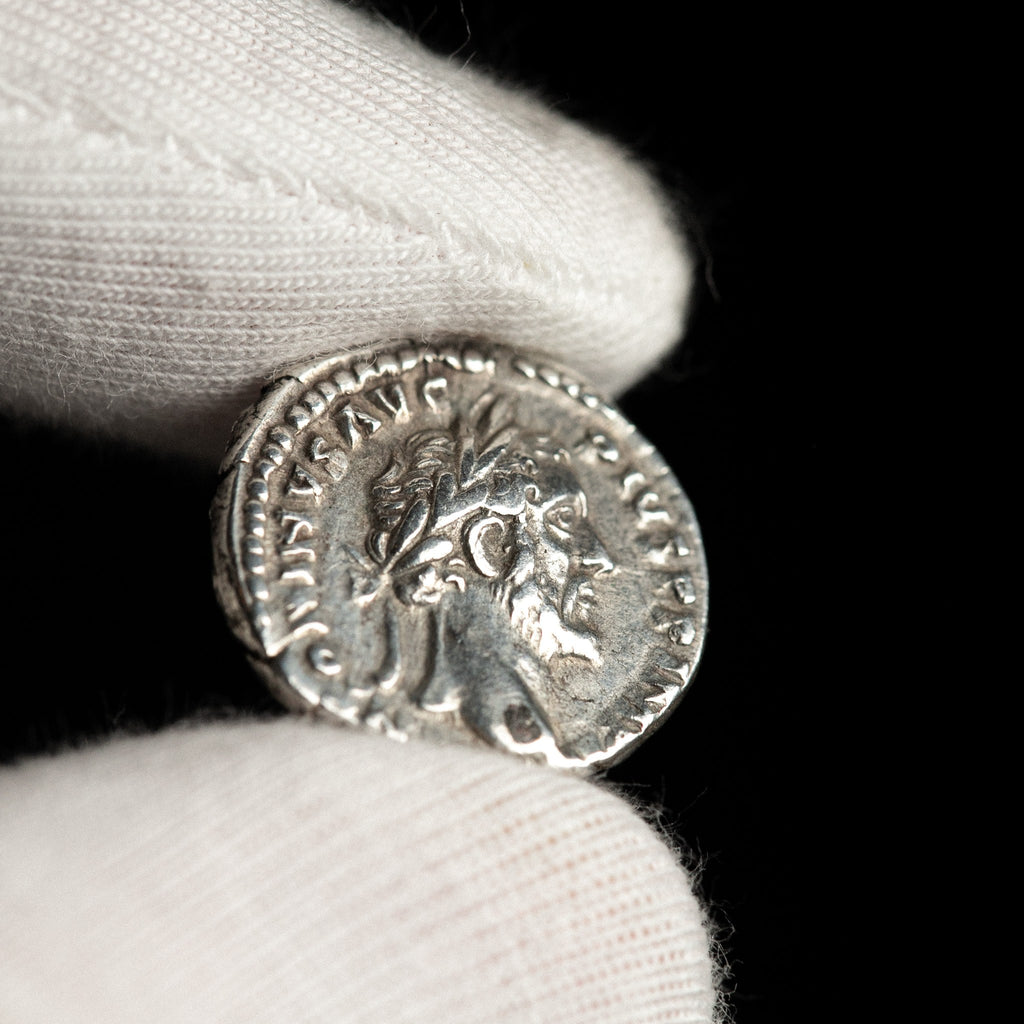 Roman silver denarius of Antoninus Pius shown in hand for context.