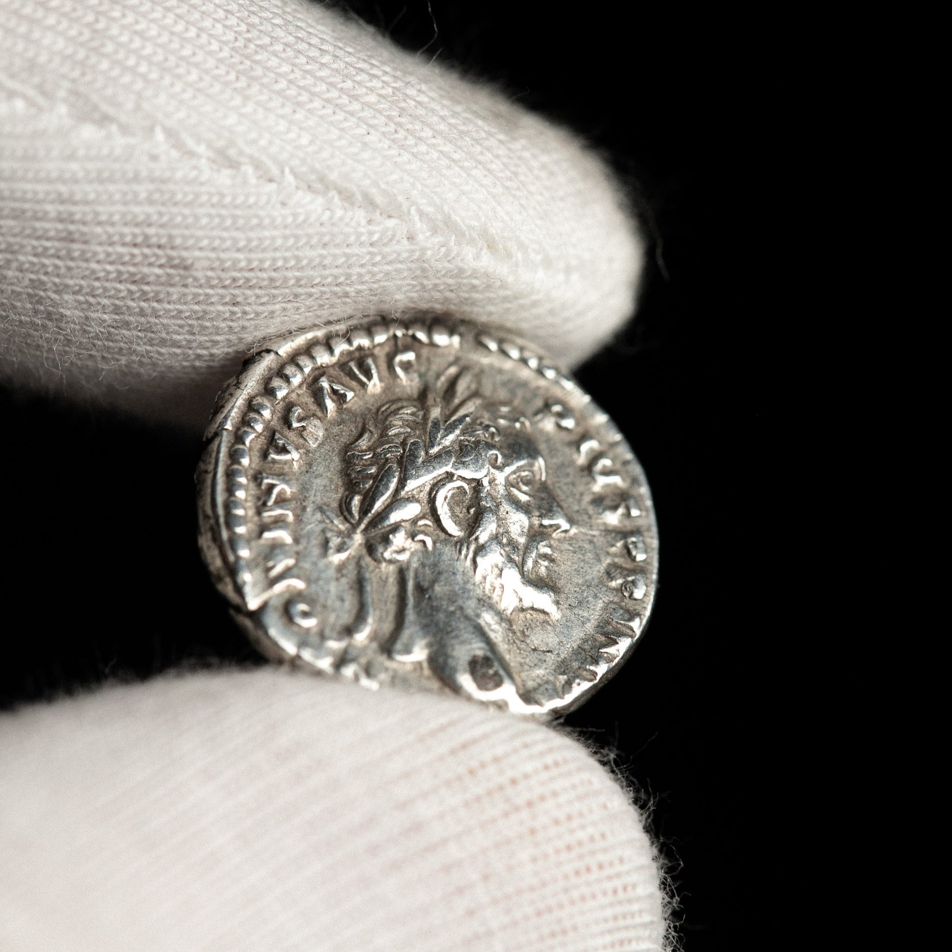 Roman silver denarius of Antoninus Pius shown in hand for context.