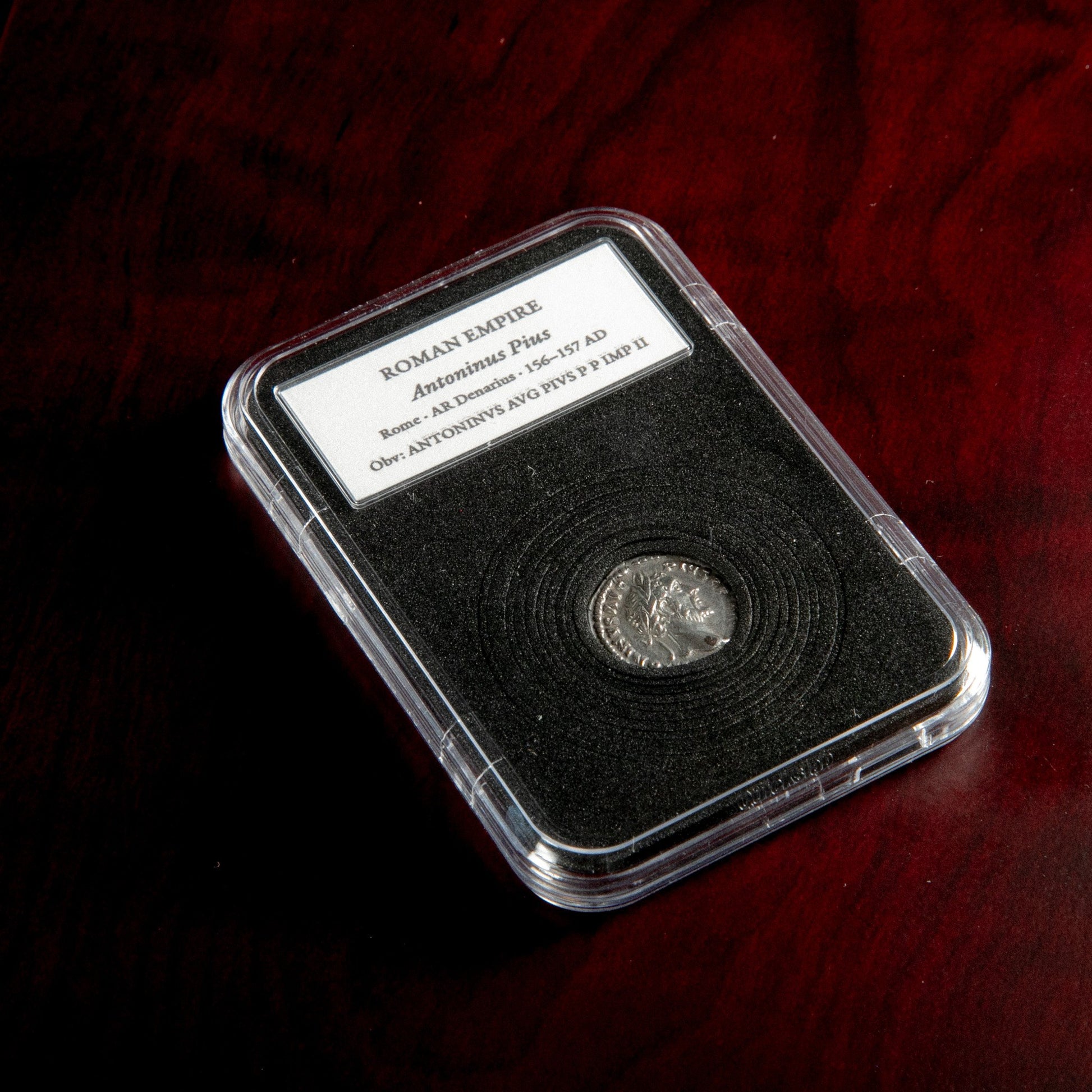 Roman silver denarius of Antoninus Pius in protective slab with catalog label.