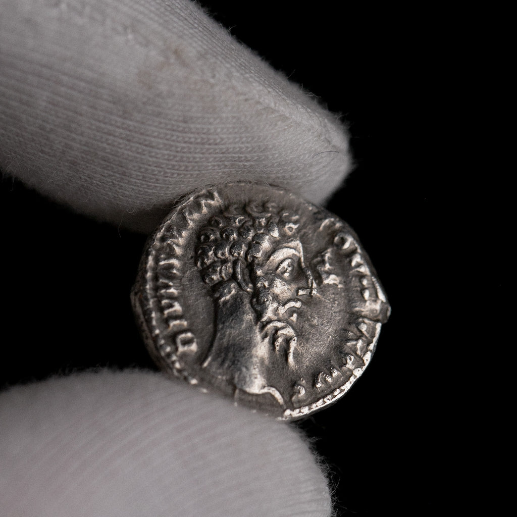 Roman silver denarius of Divus Marcus Aurelius (under Commodus) shown in hand for context.