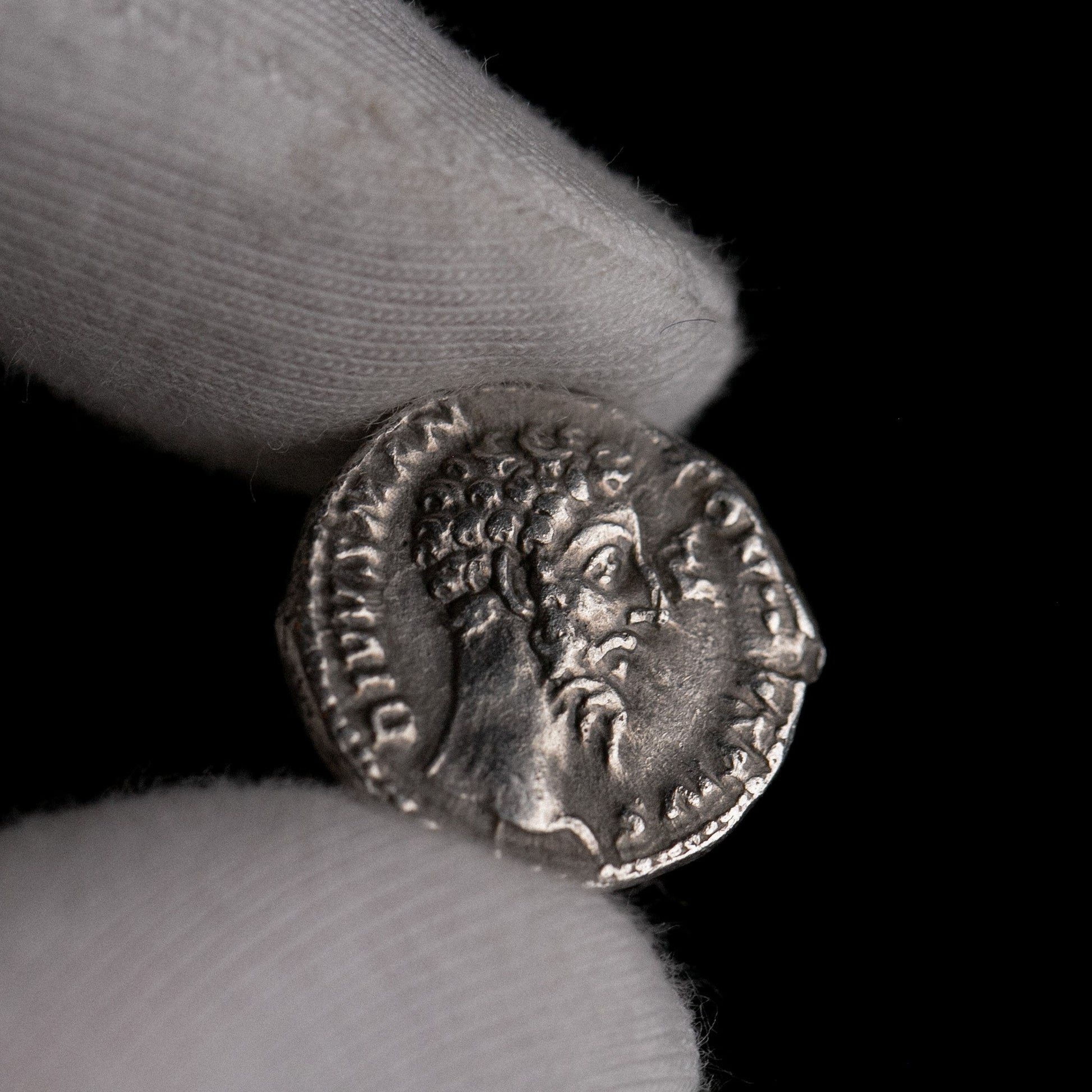 Roman silver denarius of Divus Marcus Aurelius (under Commodus) shown in hand for context.