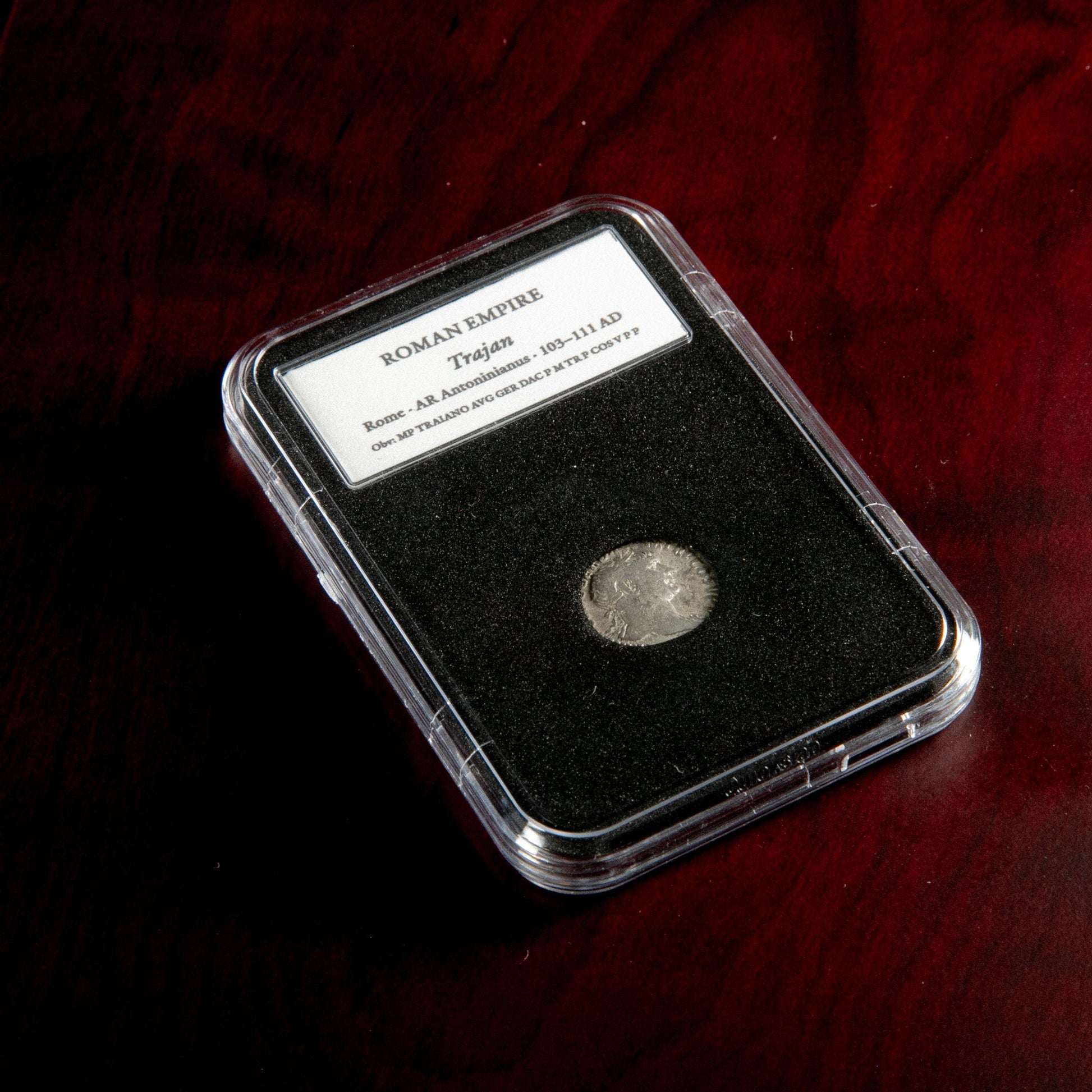 Roman silver denarius of Trajan in protective slab with catalog label.