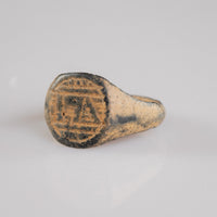 Medieval bronze signet ring Falco, angled top view of monogram engraving within circular border