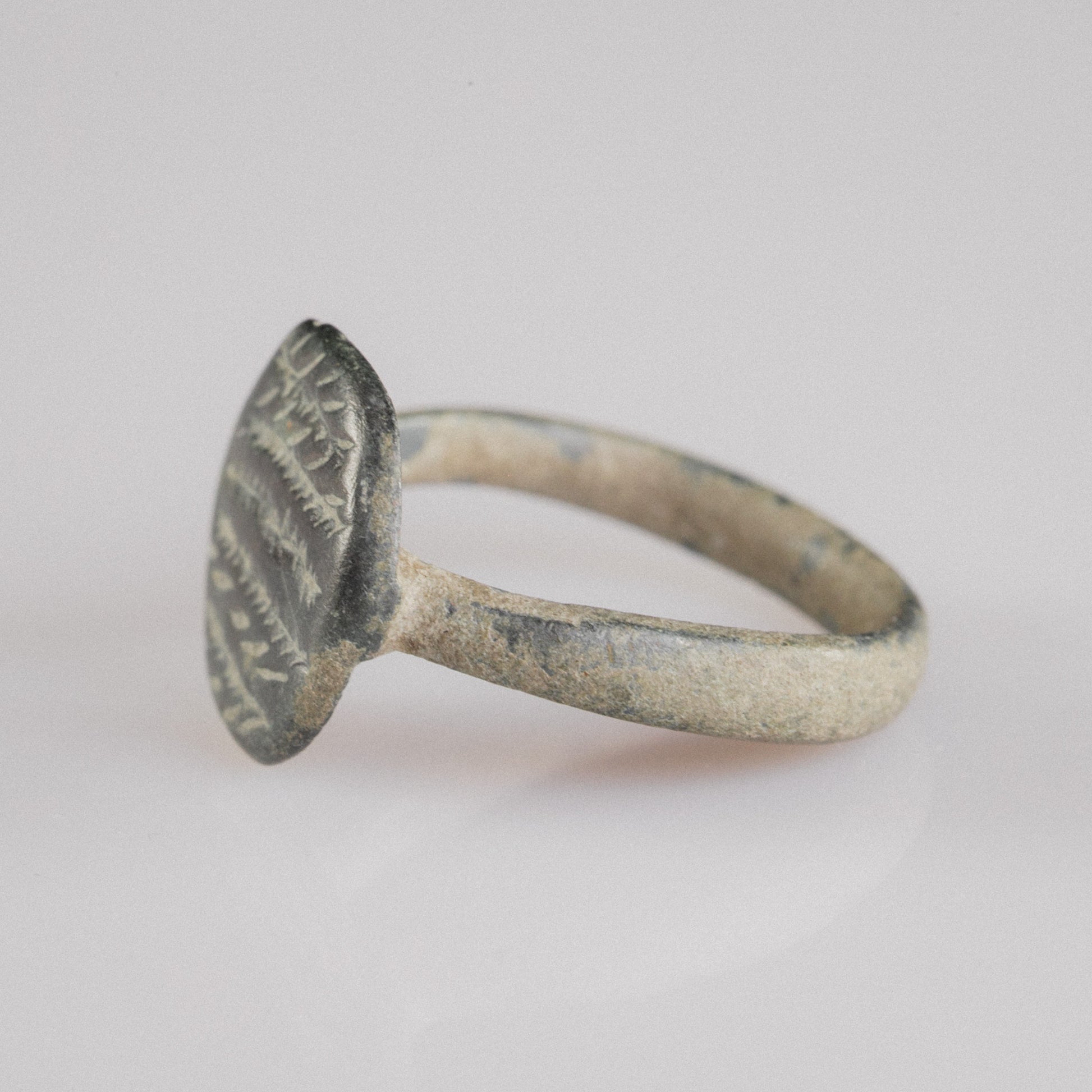 Roman bronze ring Frondis, three-quarter view highlighting engraved bezel and green patina