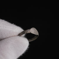Close-up of Medieval silver ring Aldwin held in gloved hand, showing bezel wear