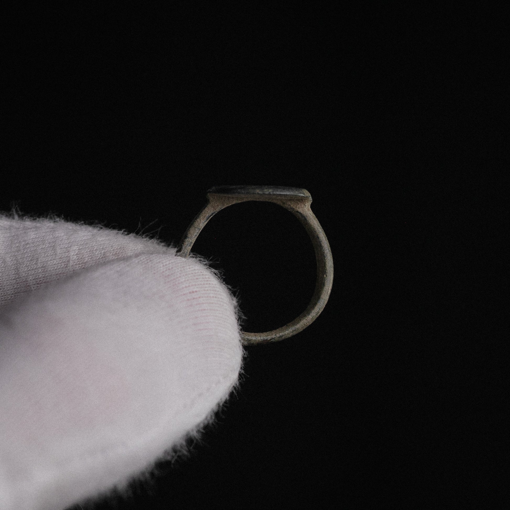 Studio close-up of Roman bronze ring Frondis in profile showing hoop taper and bezel setting