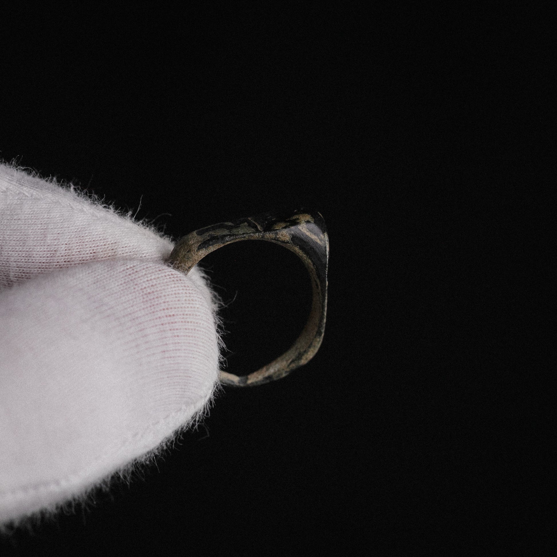 Roman bronze ring Numeria, macro view of bezel engraving held in gloved hand