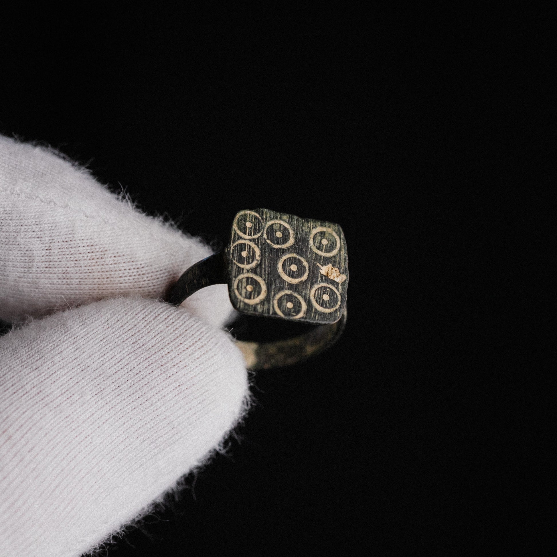 Late Roman bronze ring Novenarius held in gloved hand showing square bezel with nine ring-and-dot punches
