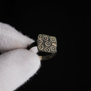 Late Roman bronze ring Novenarius held in gloved hand showing square bezel with nine ring-and-dot punches