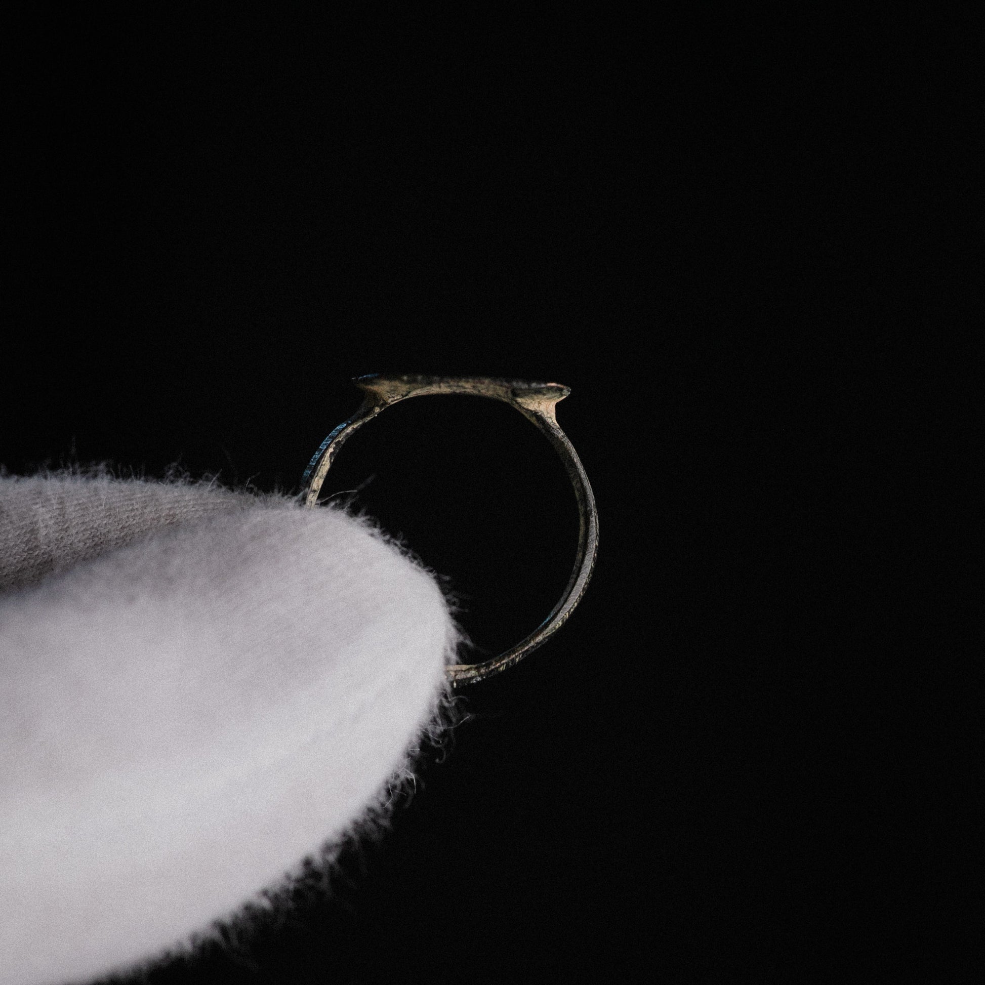 Side profile of Novenarius Late Roman bronze ring showing flat-band hoop and angular shoulders