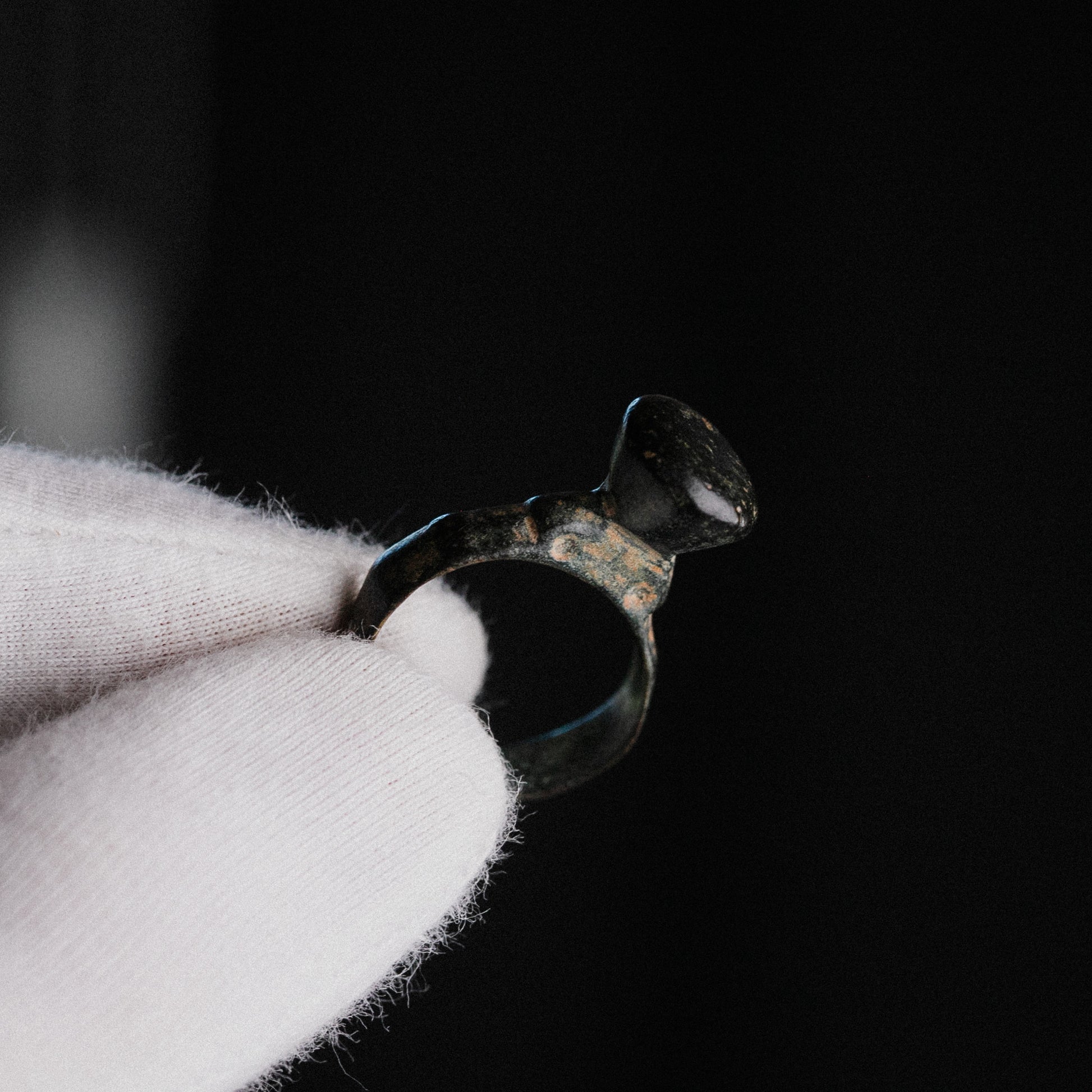 Late Roman bronze pedestal signet ring Numerius Magnus held in gloved hand, showing conical bezel profile