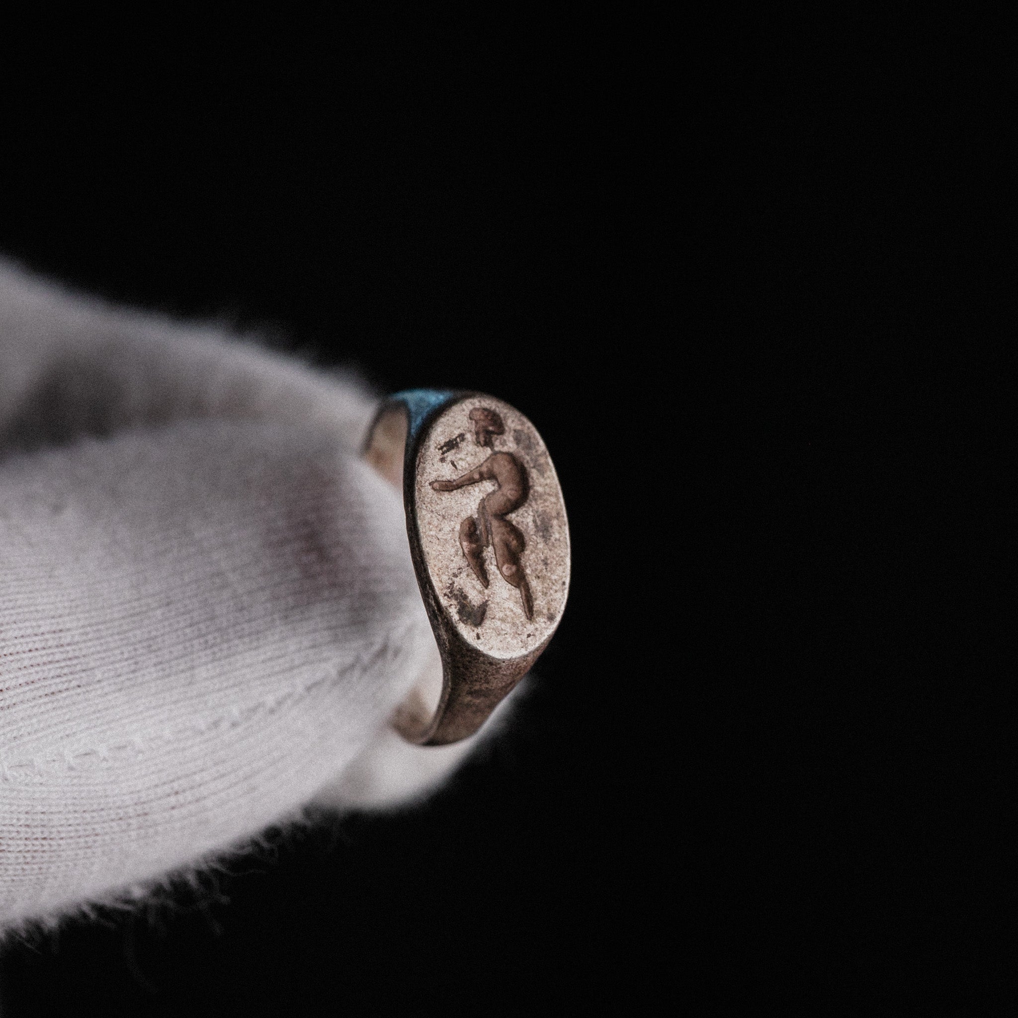 Roman silver signet ring Faunus held in gloved hand showing faun figure on oval bezel