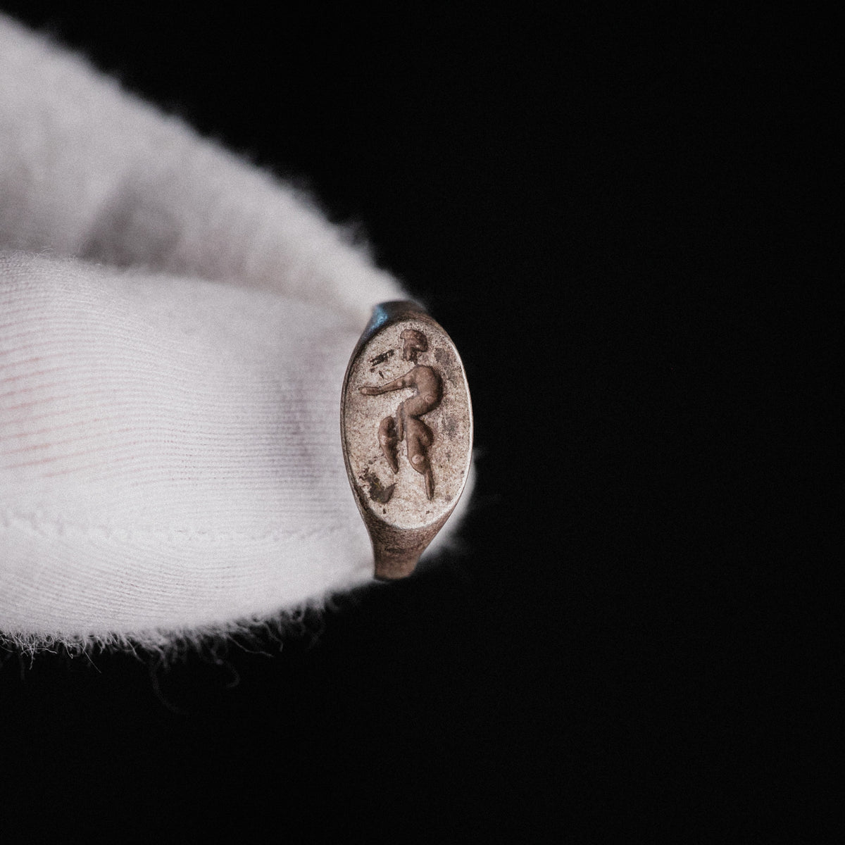 Angled view of Roman silver signet ring Faunus with patina and soil deposits visible