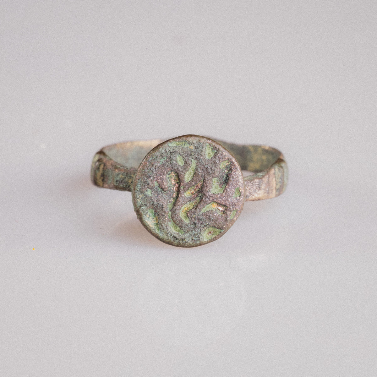 Studio view of Islamic bronze signet ring Zahir displaying flat circular bezel and tapering hoop