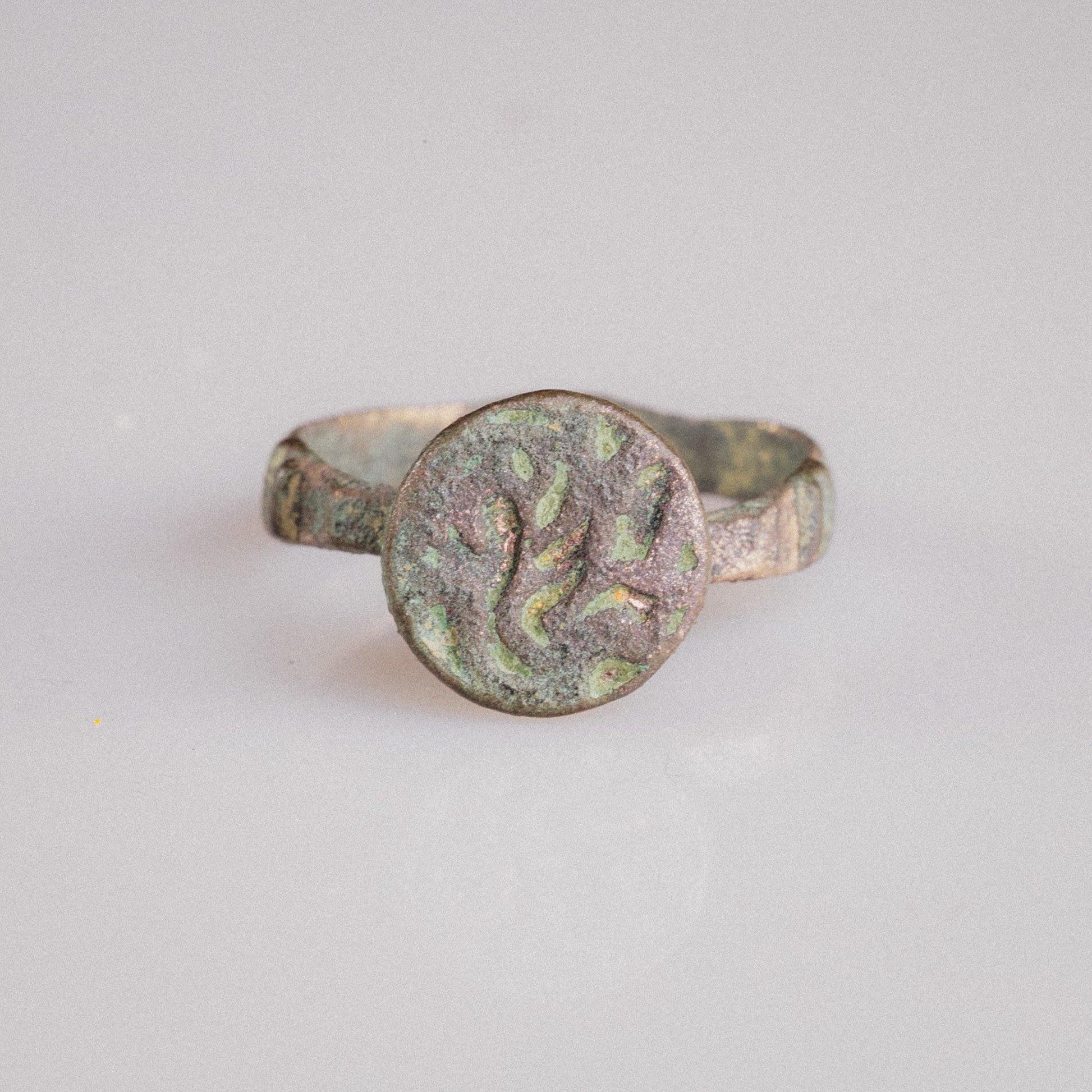 Studio view of Islamic bronze signet ring Zahir displaying flat circular bezel and tapering hoop