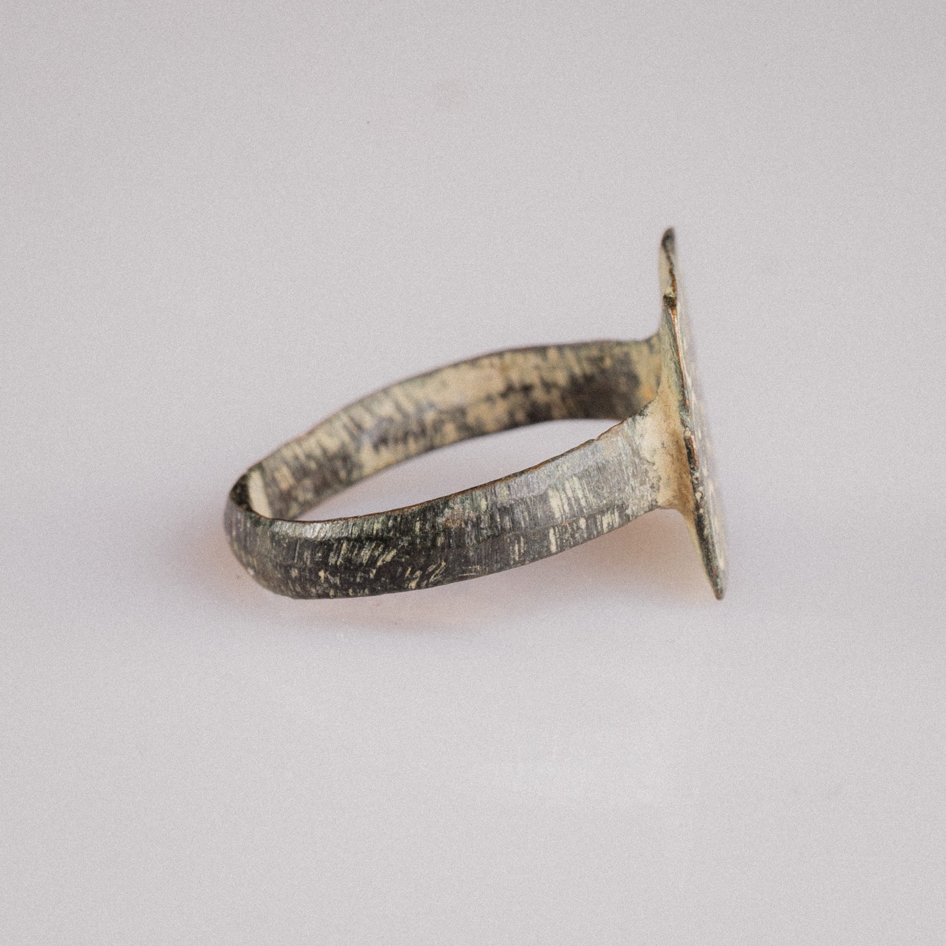 Side view of Novenarius Late Roman bronze ring showing hoop taper and burial patina