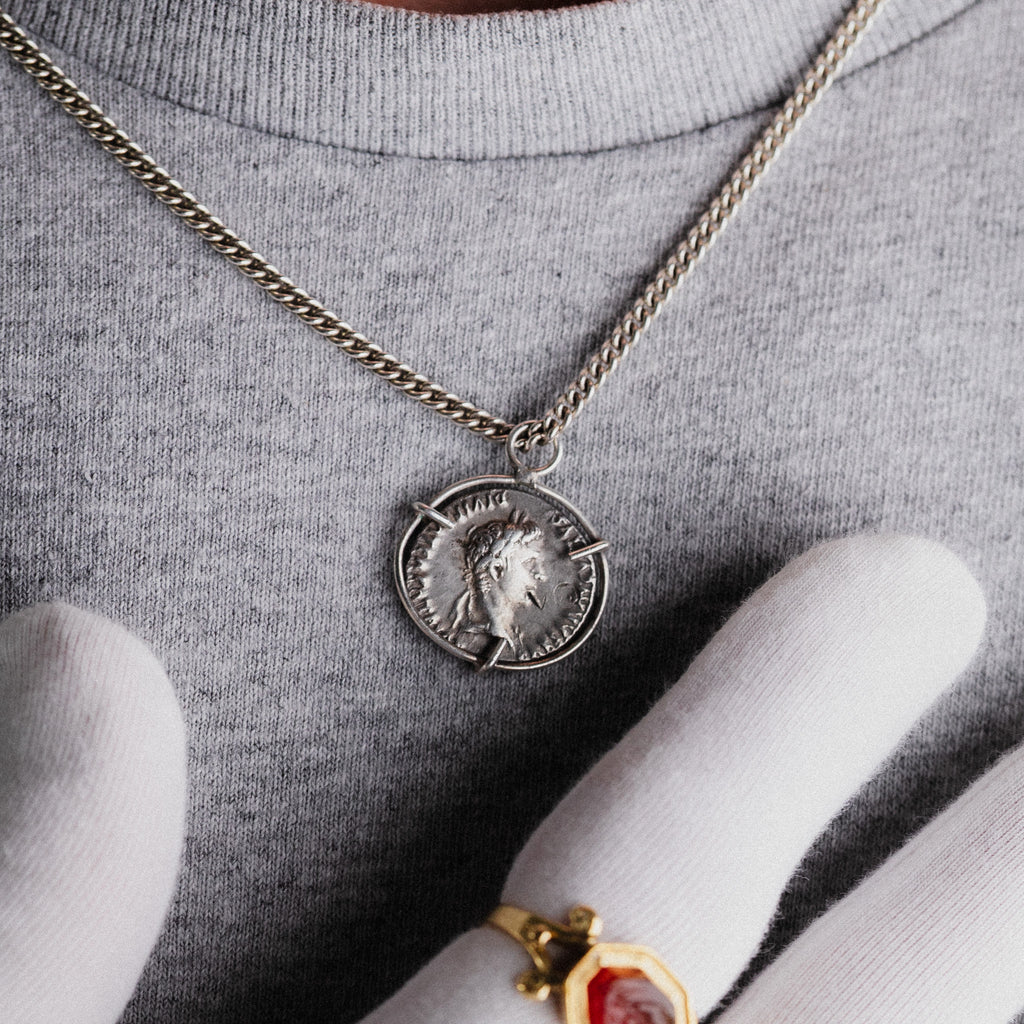Hand holding Roman silver coins and an antique gold pendant — Aurora Antiqua coin collection