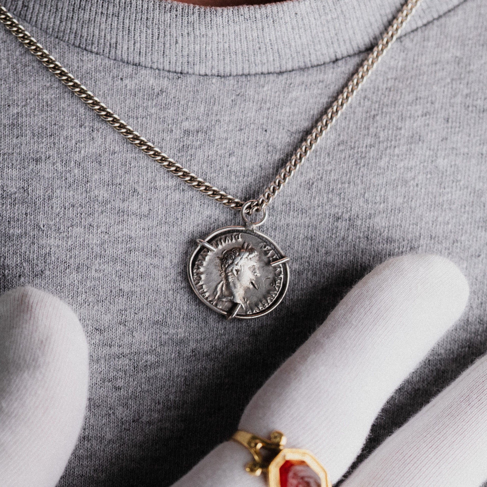 Hand holding Roman silver coins and an antique gold pendant — Aurora Antiqua coin collection