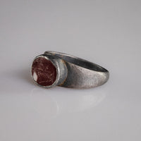 Close-up of Roman silver ring Sereia held in gloved hand, garnet intaglio detail visible