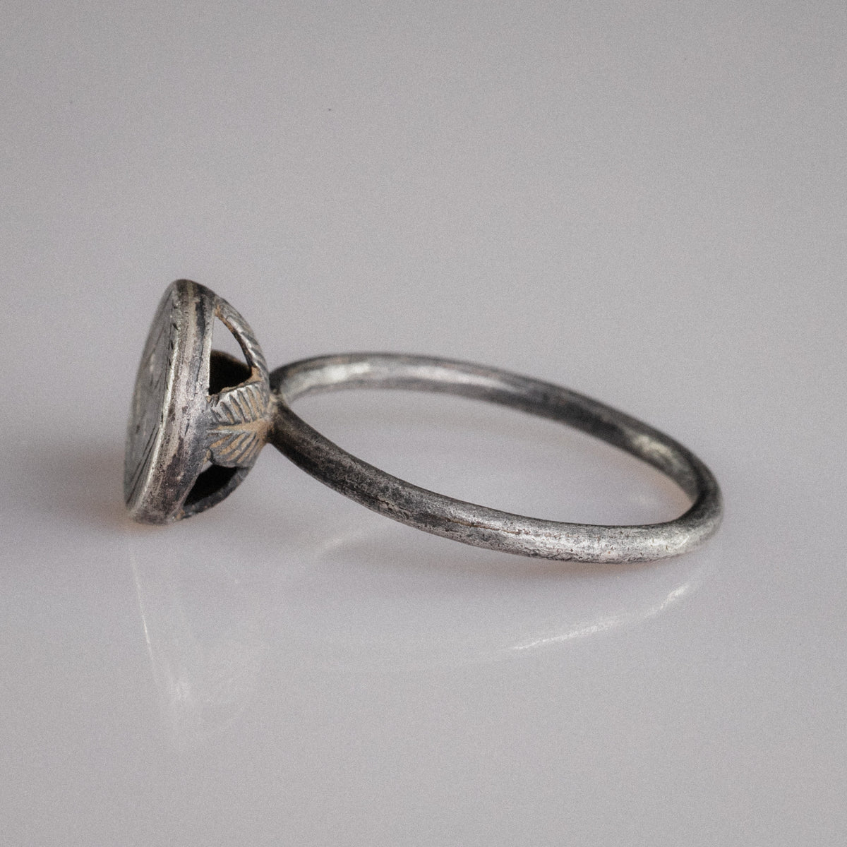 Angled view of Byzantine silver ring Crucia with slender wire hoop and disc bezel