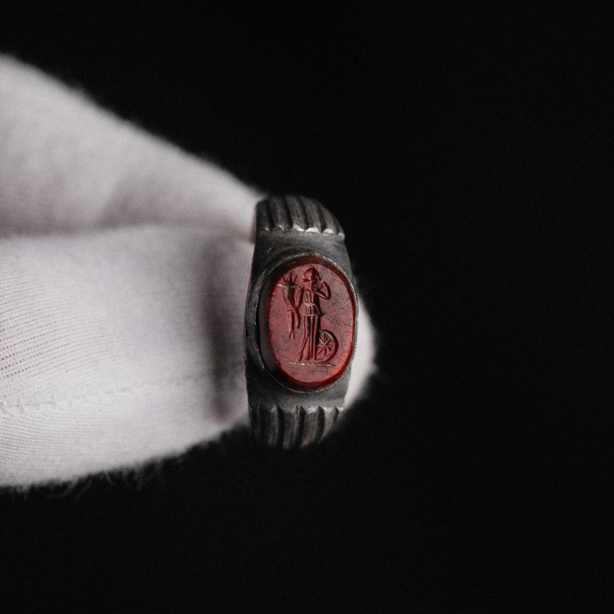 Dramatic detail of red jasper Fortuna intaglio on Roman silver ring Fortunata against black